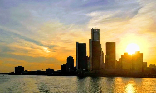 The sun rising behind the skyline of Detroit viewed from the river.