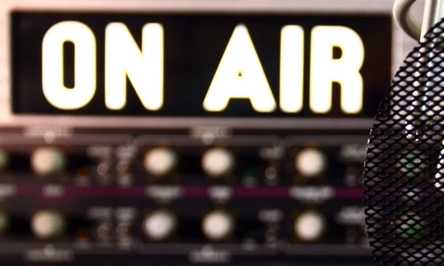 Microphone in front of recording studio with "on air" sign