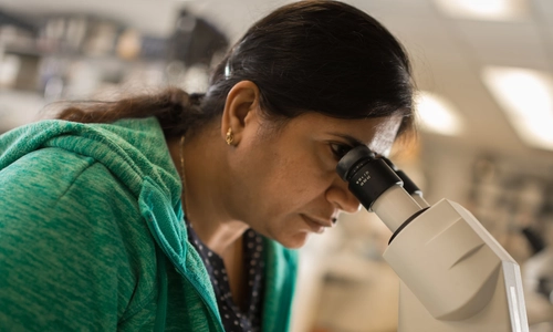 woman looking into a microscope