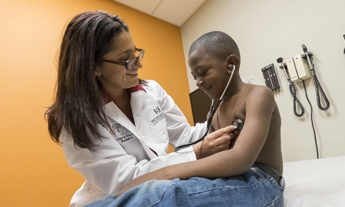 Mona Hana using a stethoscope on a child in an exam room
