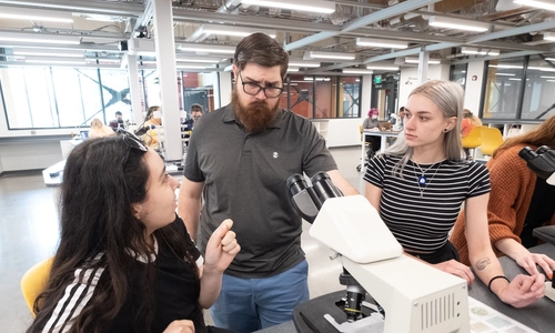 Teacher helping students looking at microscopes