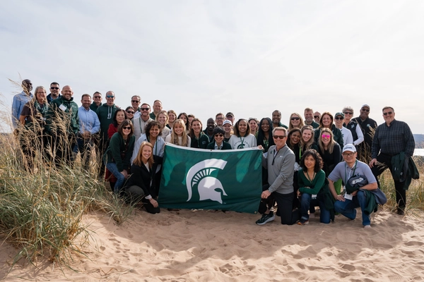 Group of people on a beach with a Spartan flag.